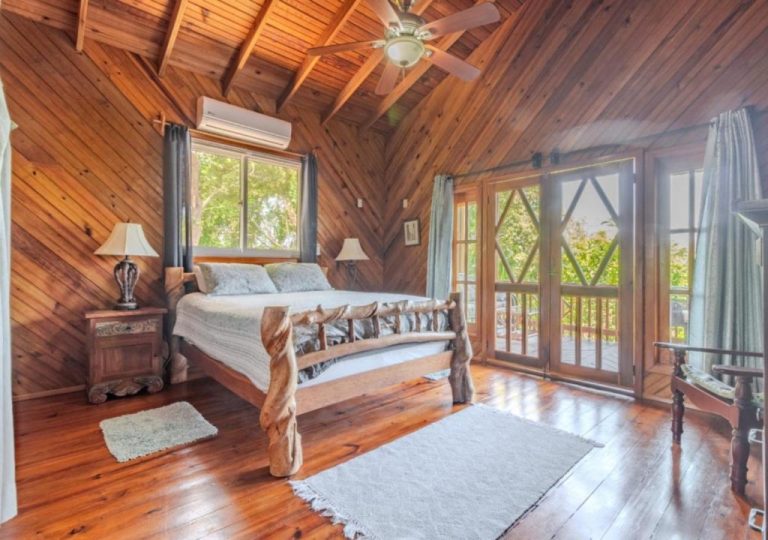 Habitación rústica con cama de madera artesanal y techo de vigas en Guava Grove Resort & Villas