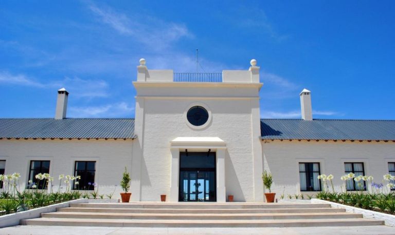 Fachada principal blanca con escalinata de acceso y jardines del Hotel Santa Cristina