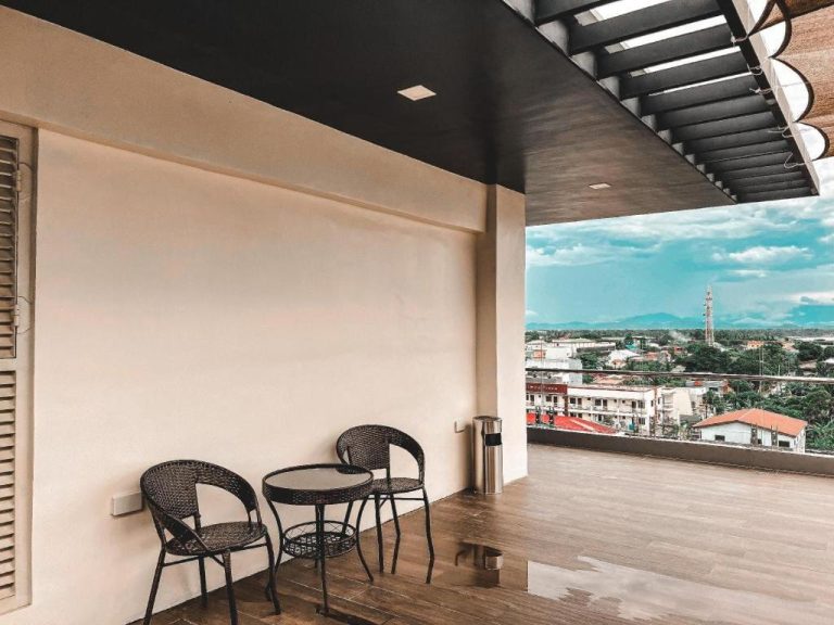 Terraza con sillas de ratán y mesa en Lavero Suites con vistas panorámicas a la ciudad y montañas