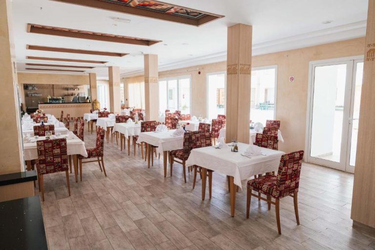 Elegante restaurante interior del Capsa Thermal Oasis con mesas blancas y sillas tapizadas en rojo