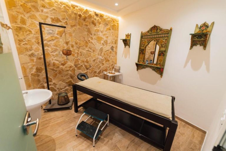 Sala de masajes con camilla y pared de piedra natural en el spa del Capsa Thermal Oasis