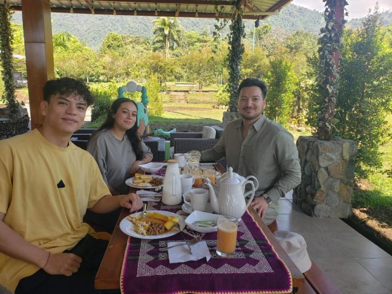Tres huéspedes disfrutando del desayuno en la terraza con vista al jardín de La Quinta de Andrés
