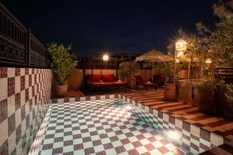 Terraza con piscina de mosaicos iluminada por la noche en Riad Tassili Boutique Marrakech