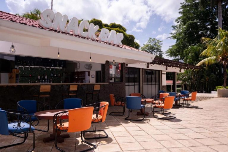 Terraza exterior del Snack Bar del Best Western Las Mercedes Airport con mesas y sillas coloridas