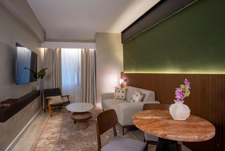 Salón de suite en Amari by Vivere con mesa de mármol, sofá y pared verde con iluminación