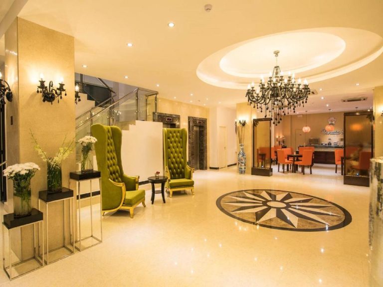 Elegante lobby del Palms Hotel con sillones verdes, suelo marmol y lujosa araña de cristal
