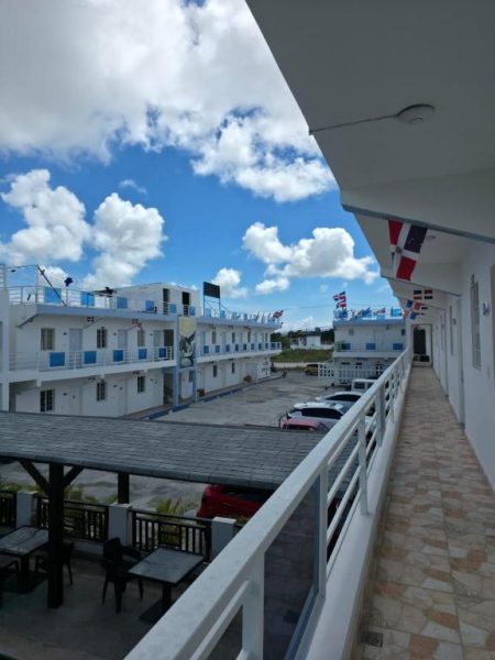 Vista desde el balcón exterior del Costa Love Hotel Aeropuerto con banderas dominicanas y edificios blancos