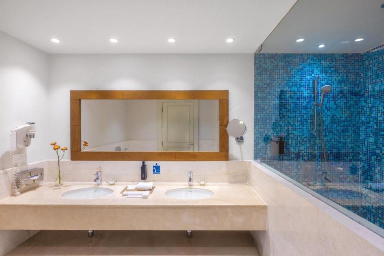 Baño de lujo con doble lavabo en mármol y ducha con mosaicos azules en Sifawy Boutique Hotel
