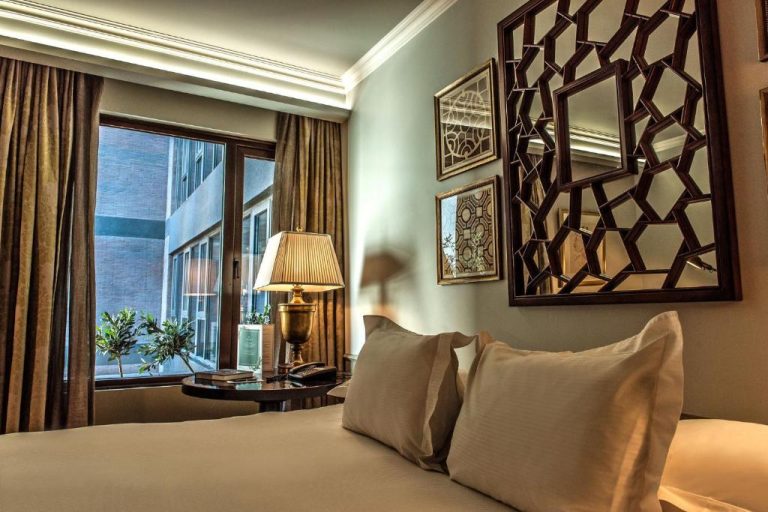 Habitación elegante con cama doble, espejo decorativo y ventana en The Singular Santiago
