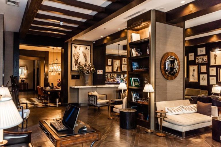 Elegante lobby bar del hotel The Singular Santiago con sofás, librería y decoración clásica de lujo