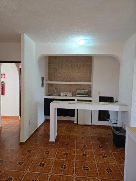 Cocina equipada con barra de desayuno y fregadero en Íkaro Suites Cancún