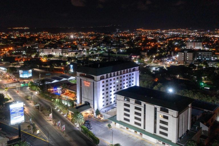 Vista aérea nocturna del Clarion Hotel Real Tegucigalpa iluminado con panorámica de la ciudad de fondo