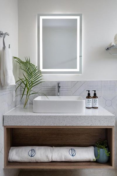 Baño moderno con lavabo sobre encimera y espejo LED iluminado en Negril Footprints Hotel