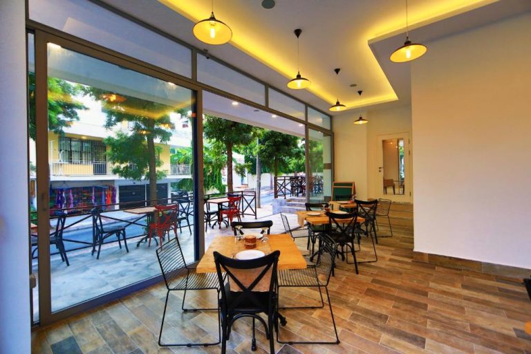 Restaurante interior con terraza exterior y mesas de madera en el Perle Apart Hotel