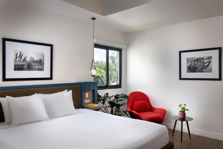 Habitación doble moderna con silla roja y arte en paredes del Negril Footprints Hotel en Jamaica