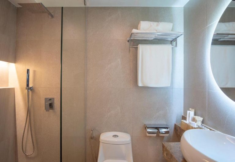 Baño moderno con ducha de lluvia, inodoro y espejo retroiluminado en Hotel Amari By Vivere Hospitality Group