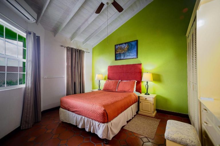 Habitación doble con pared verde, cama roja y ventilador de techo en Best E Villas Prospect St James