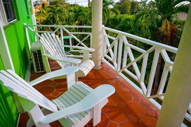 Terraza con sillas blancas y vistas a jardín tropical en Best E Villas Prospect St James Barbados