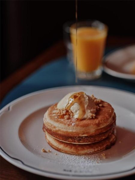 Desayuno de pancakes con mantequilla y sirope en The EVE Hotel Sydney acompañado de zumo de naranja