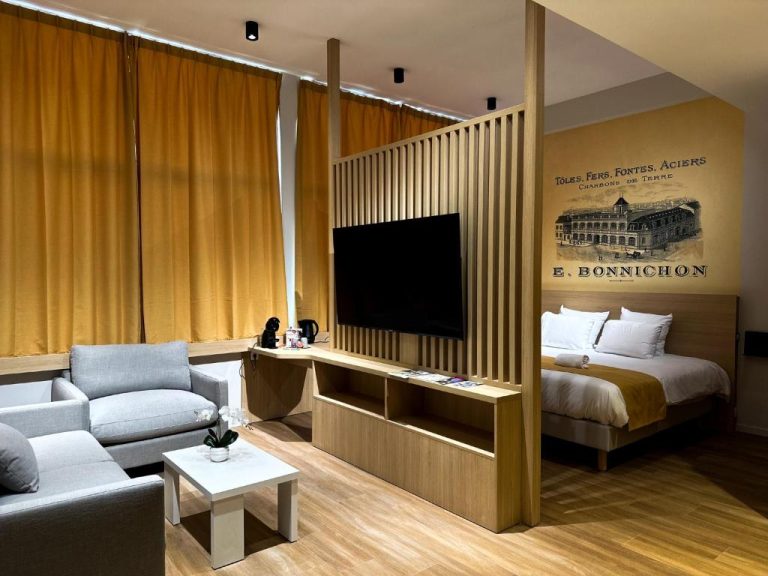 Suite del Hotel Le Noirlac con zona de salón, televisión y cama doble con decoración vintage