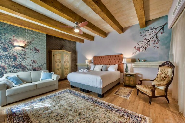 Habitación superior con vigas de madera y murales florales en Palazzo Consiglia IK Collection