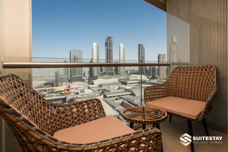 Balcón con sillas de ratán y vistas al skyline de Dubai en Fashion Avenue Dubai Mall The Residence