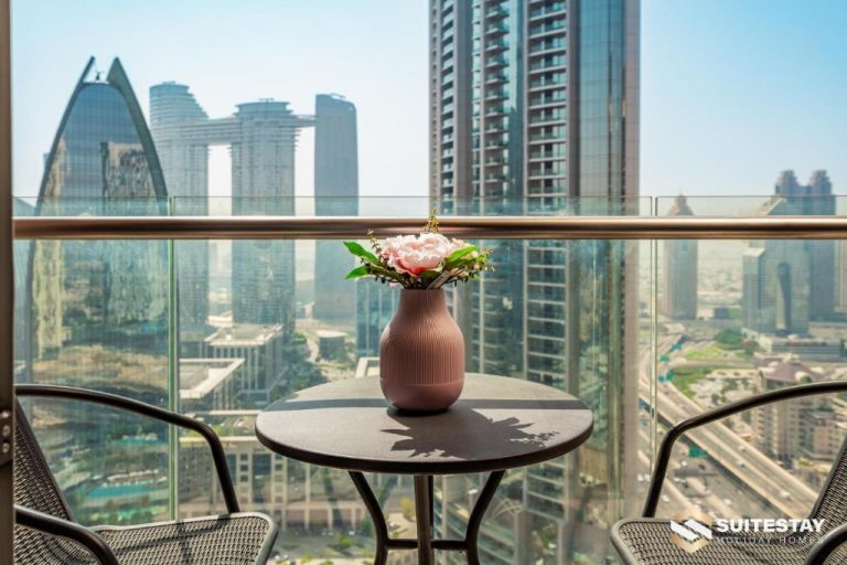 Balcón con mesa y flores del Fashion Avenue Dubai Mall The Residence con vistas panorámicas a los rascacielos
