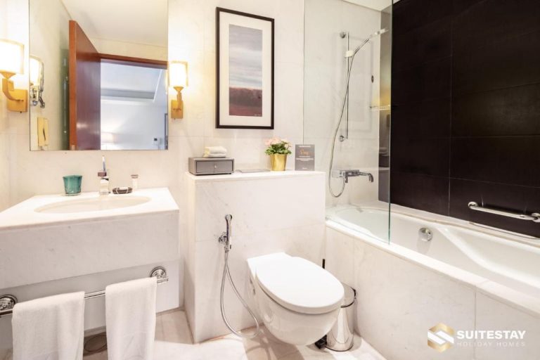Baño de mármol blanco con bañera y ducha en Fashion Avenue Dubai Mall The Residence