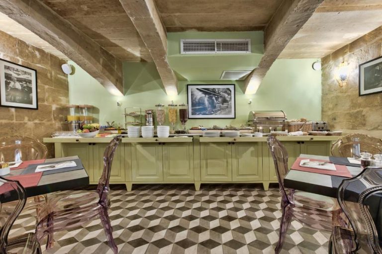 Zona de buffet de desayuno con mobiliario verde y suelo geométrico en Palazzo Consiglia IK Collection