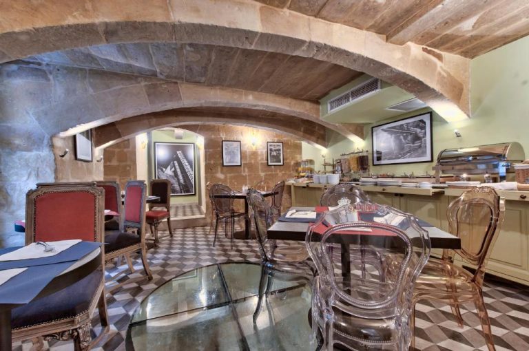 Restaurante con arcos de piedra y mesas de cristal en el Palazzo Consiglia IK Collection Malta