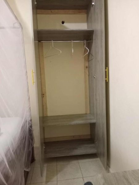 Armario empotrado de madera con perchas y estantes en habitación del Hotel Villa De Leo