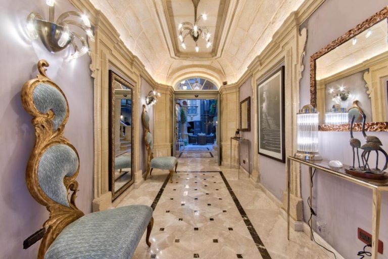 Elegante pasillo de mármol con decoración barroca y espejos dorados en Palazzo Consiglia IK Collection