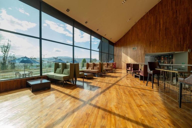 Amplio lobby con ventanales panorámicos y suelos de madera del Wyndham Quito Airport
