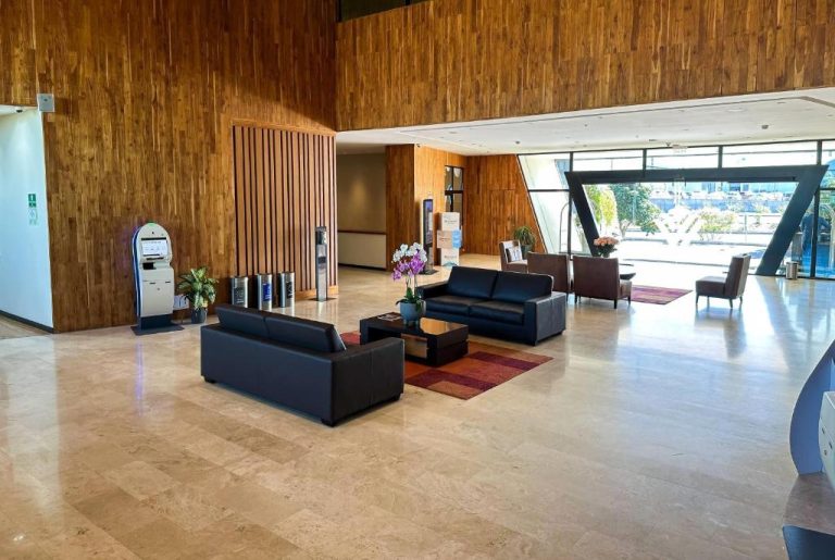 Amplio lobby con sofás de cuero y paredes de madera del hotel Wyndham Quito Airport