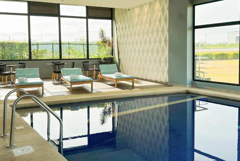 Piscina interior climatizada con tumbonas y vistas panorámicas del Wyndham Quito Airport