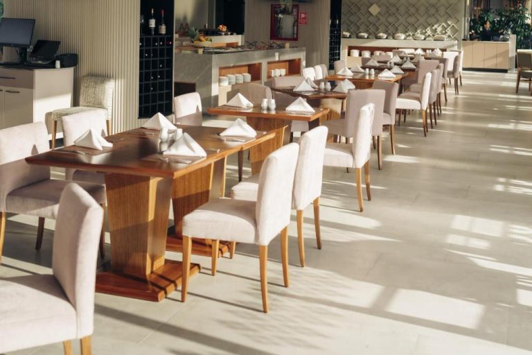 Elegante restaurante interior del Wyndham Quito Airport con mesas de madera y sillas tapizadas en beige