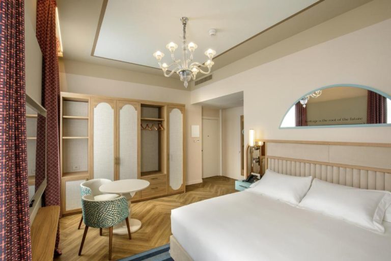 Habitación deluxe con cama doble, lámpara de araña y armarios de madera en Rosetta Hotel Perugia Hilton