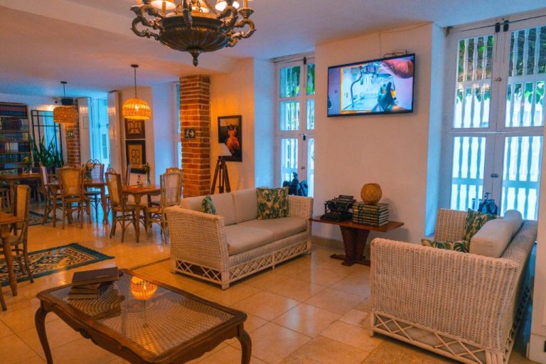 Sala de estar con sofás de mimbre y decoración colonial en el Hotel Kartaxa Cartagena