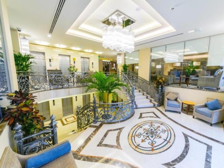 Lujoso lobby con escalera de hierro forjado y suelo de mármol del Gulf Pearls Hotel