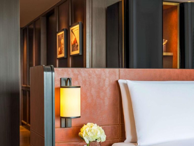 Habitación de lujo con cabecero de cuero y lámpara de pared en el Fairmont Singapore
