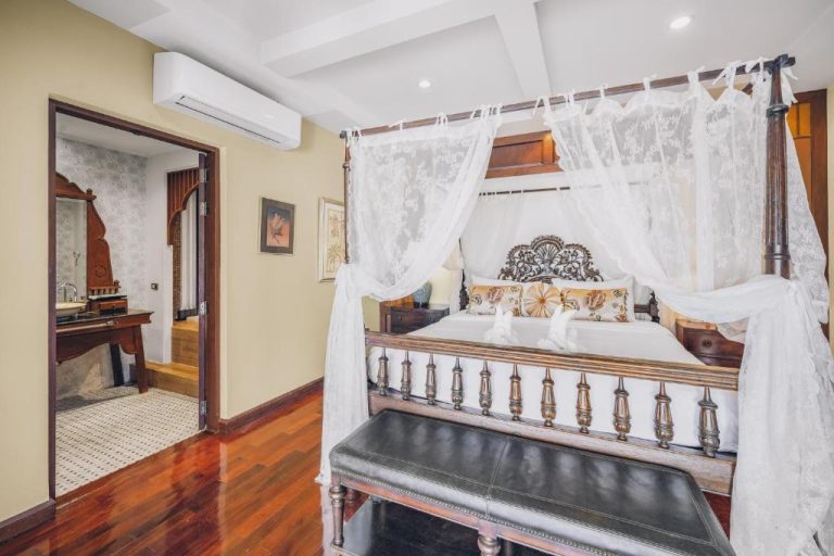 Habitación con cama de dosel de madera tallada y cortinas blancas en Leva Boutique Hotel