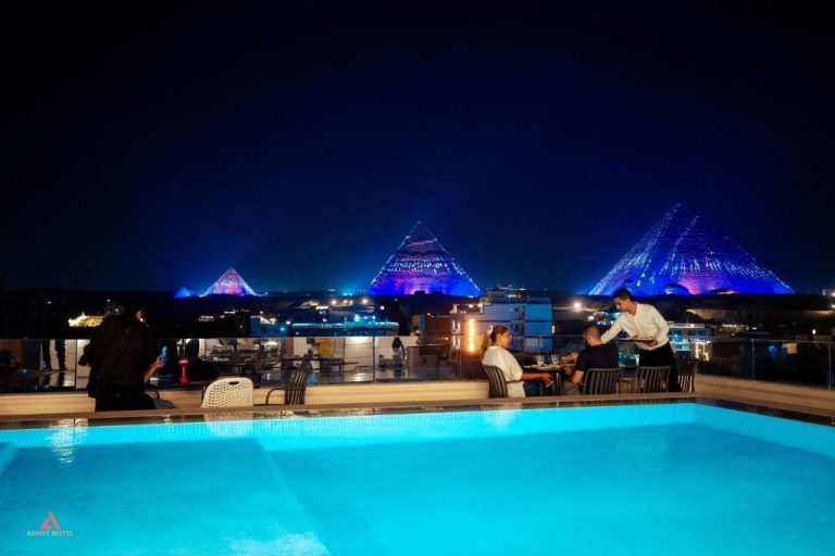 Piscina exterior con vistas nocturnas a las Pirámides de Giza iluminadas en el Kemet Pyramids View Hotel