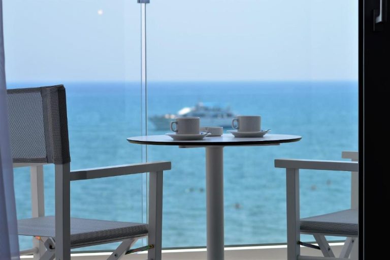 Terraza con mesa y tazas de café con vistas al mar azul en Island Boutique Hotel