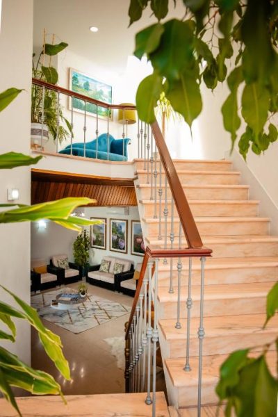 Escalera de mármol con barandilla de madera y salón interior con plantas en Hotel Larverde