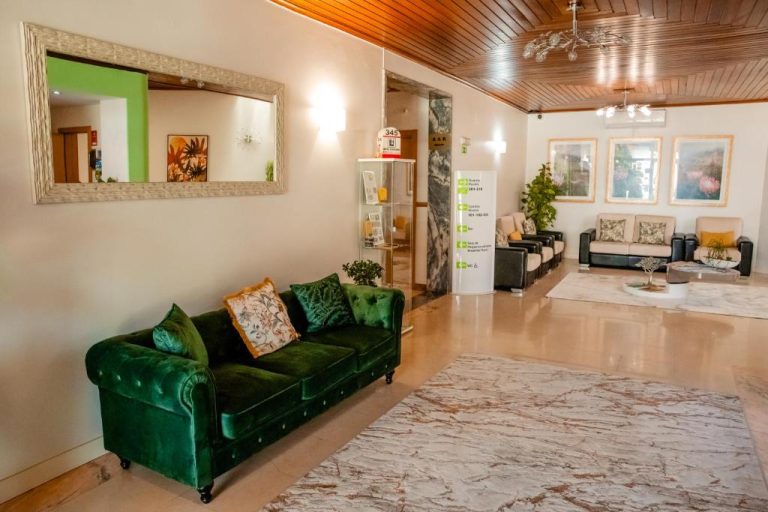 Elegante lobby del Hotel Larverde con sofá de terciopelo verde y zona de recepción iluminada