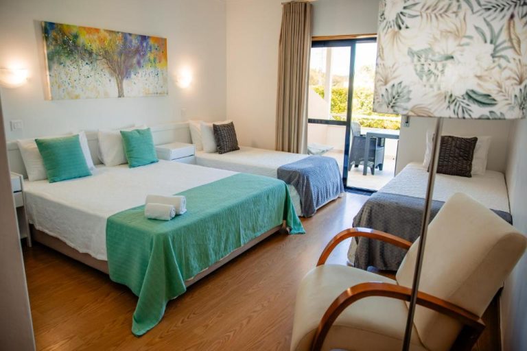 Habitación triple con camas y terraza exterior en Hotel Larverde, decoración moderna en tonos verdes y blancos