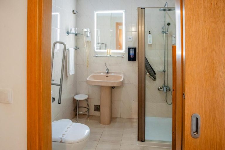 Baño adaptado con ducha accesible, lavabo y asideros de seguridad en Hotel Larverde