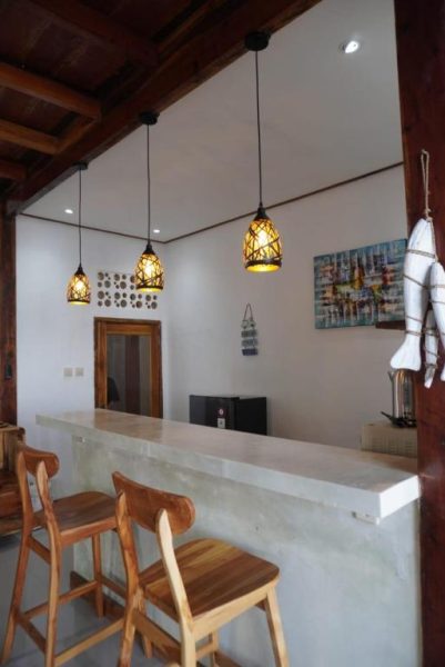 Barra de bar con taburetes de madera y lámparas decorativas en Tasola Boutique Hotel