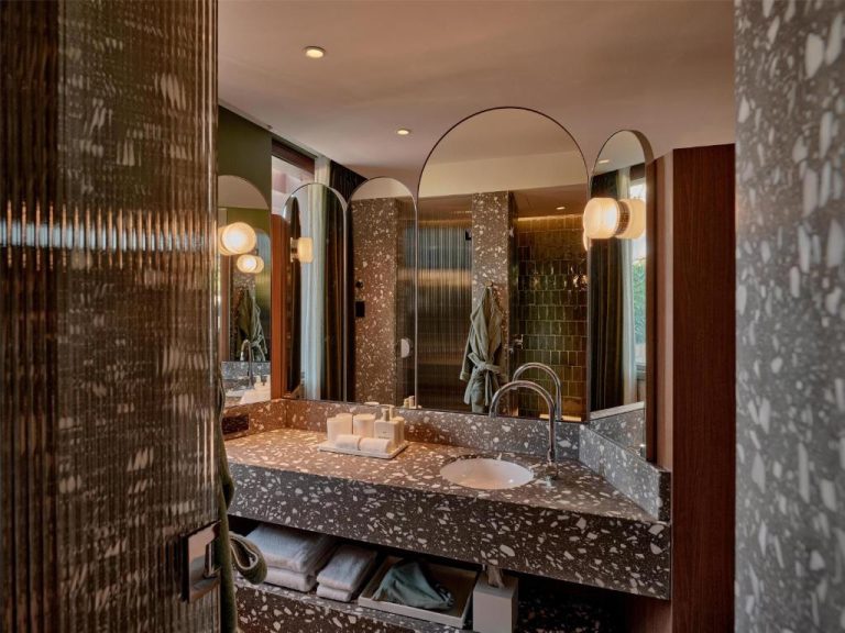 Baño de lujo con encimera de terrazzo y espejos arqueados en The EVE Hotel Sydney