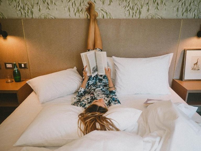 Mujer leyendo un libro relajada en la cama del Hotel Eco Boutique Bidasoa con decoración natural